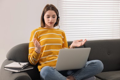 Teenager in headset having video chat via laptop at home. Remote work