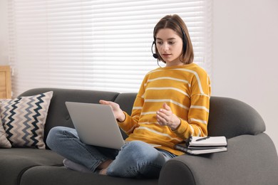 Teenager in headset having video chat via laptop at home. Remote work