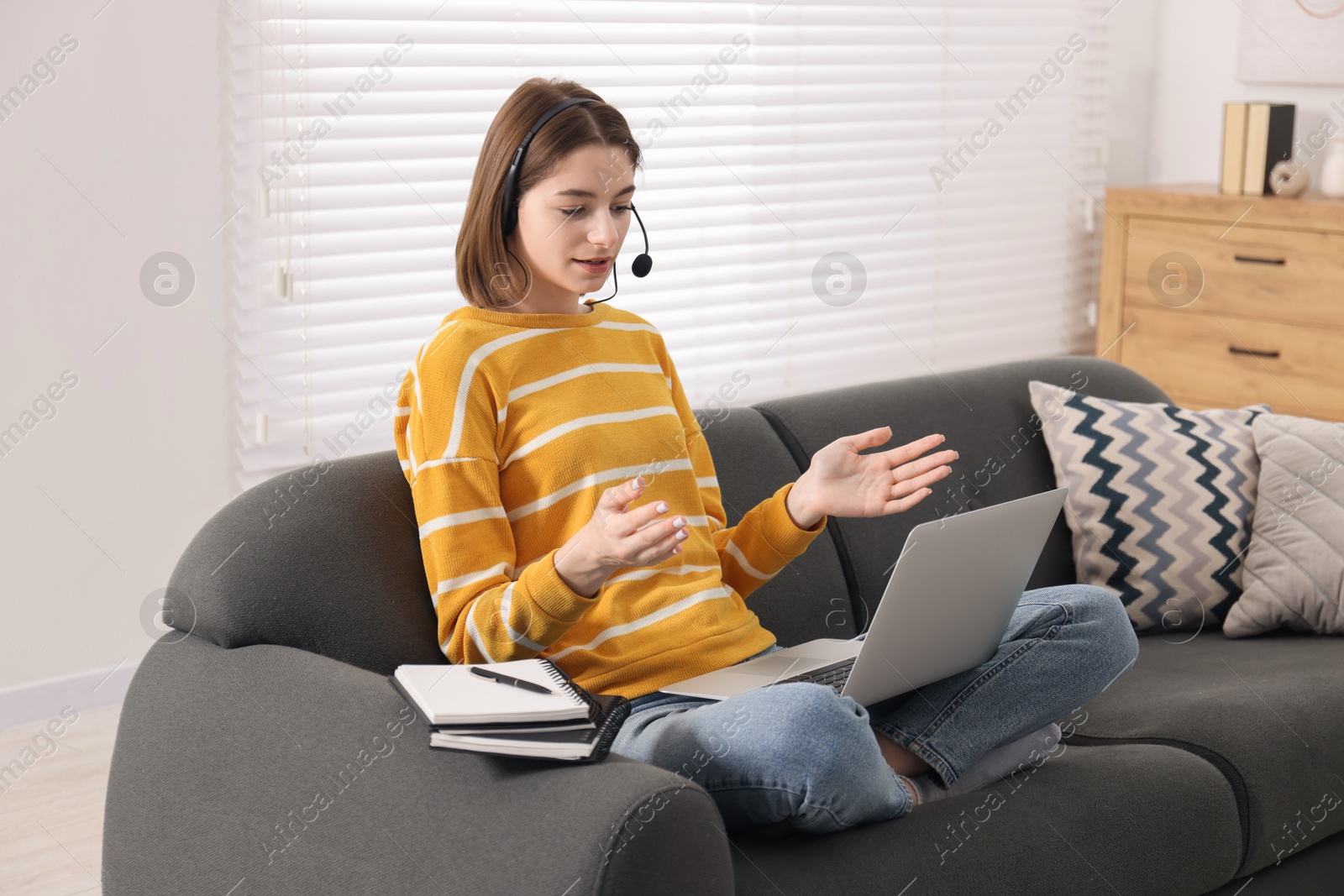 Photo of Teenager in headset having video chat via laptop at home. Remote work