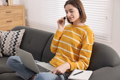 Teenager in headset having video chat via laptop at home. Remote work