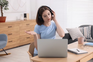 Photo of Teenager in headset having video chat via laptop at home. Remote work