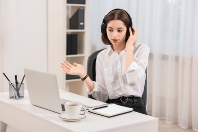 Teenager in headset having video chat via laptop at home. Remote work