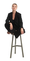 Beautiful woman in stylish suit on stool against white background