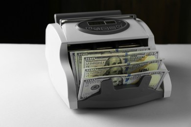 Money counter machine with dollar banknotes on light table, closeup