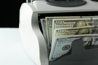 Money counter machine with dollar banknotes on light table, closeup