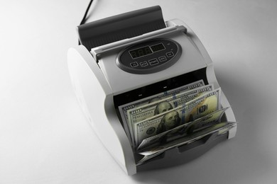 Money counter machine with dollar banknotes on light table, above view