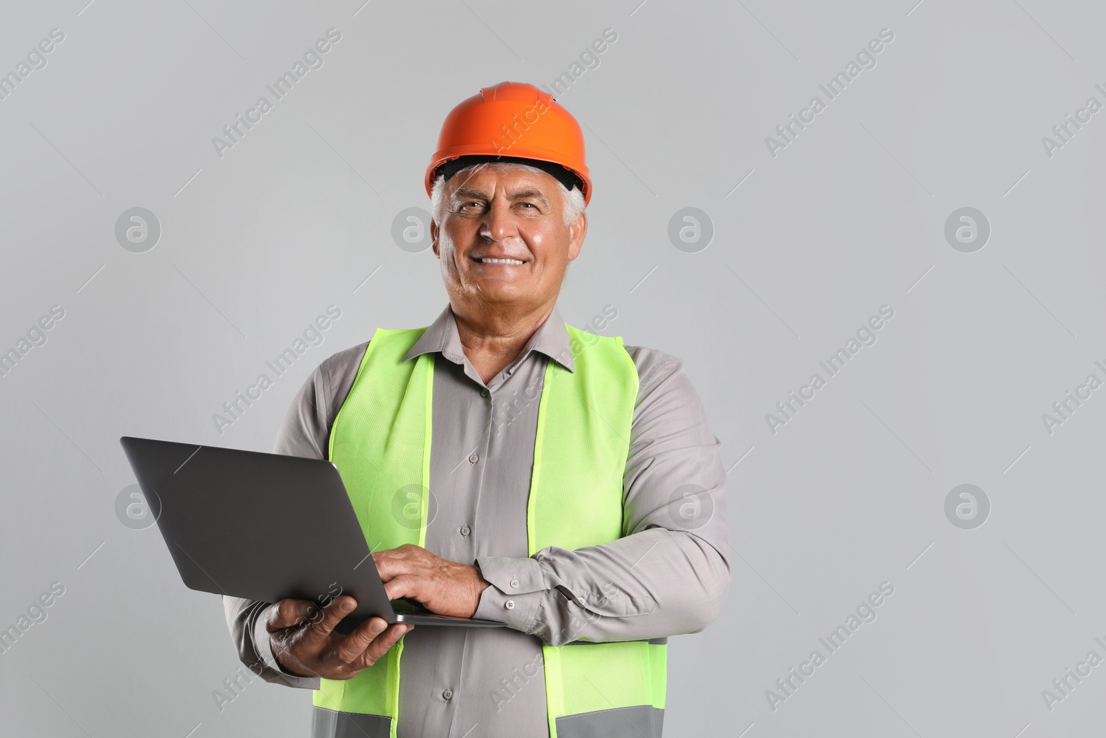 Photo of Engineer in hard hat with laptop on grey background, space for text