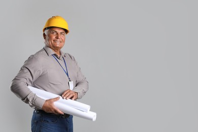 Engineer in hard hat with drafts on grey background, space for text