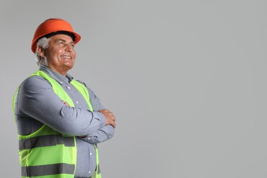 Engineer in hard hat on grey background, space for text