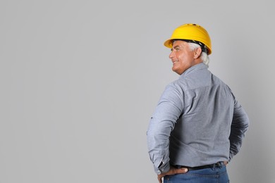 Engineer in hard hat on grey background, space for text