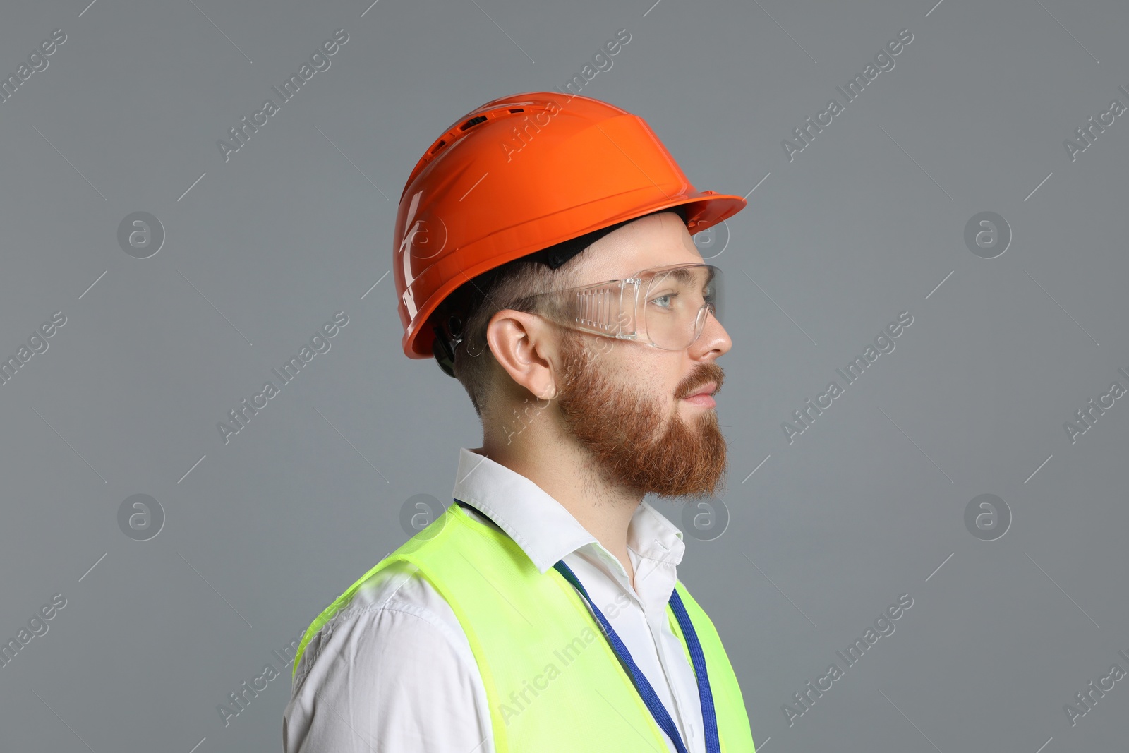 Photo of Engineer in hard hat and goggles on grey background