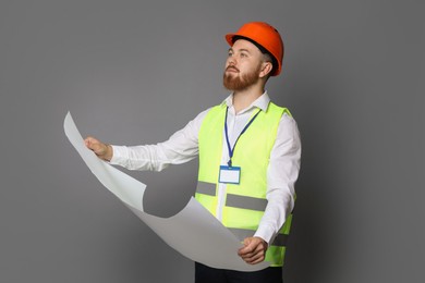 Photo of Engineer in hard hat with draft on grey background