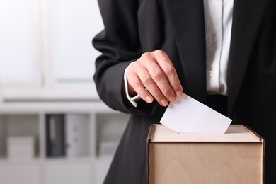 Photo of Woman putting her vote into ballot box indoors, closeup. Space for text