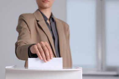 Photo of Woman putting her vote into ballot box indoors, selective focus