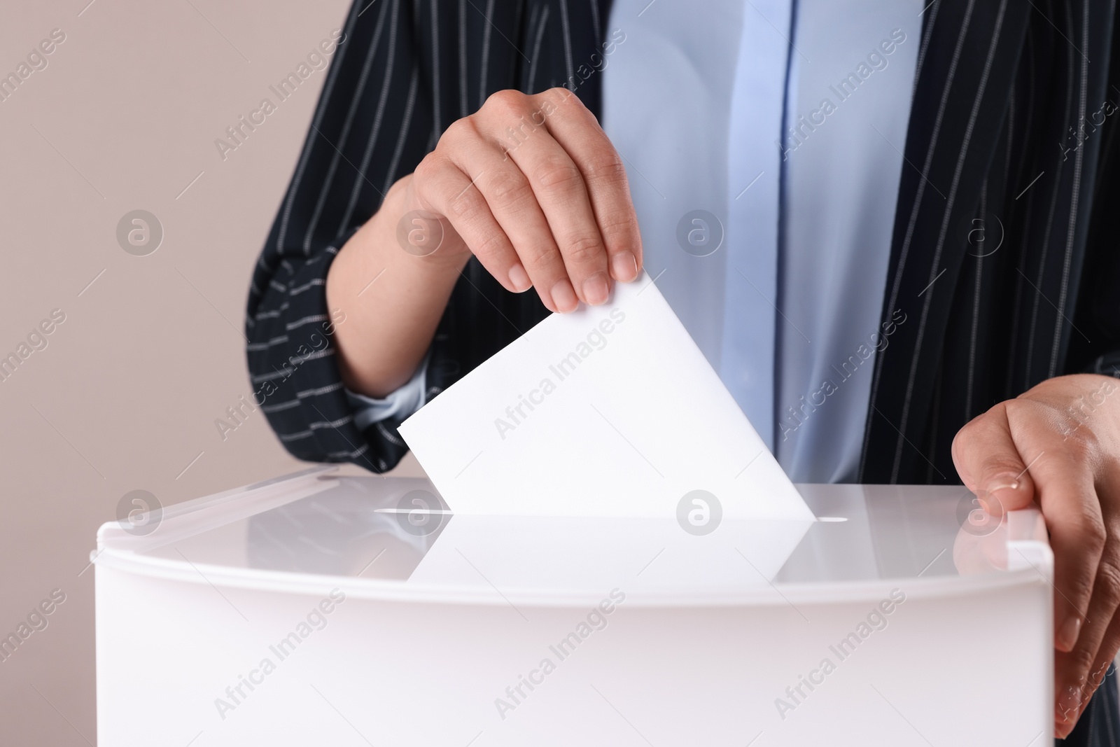 Photo of Woman putting her vote into ballot box against grey background, closeup