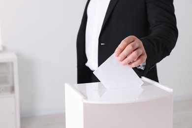 Man putting his vote into ballot box indoors, closeup