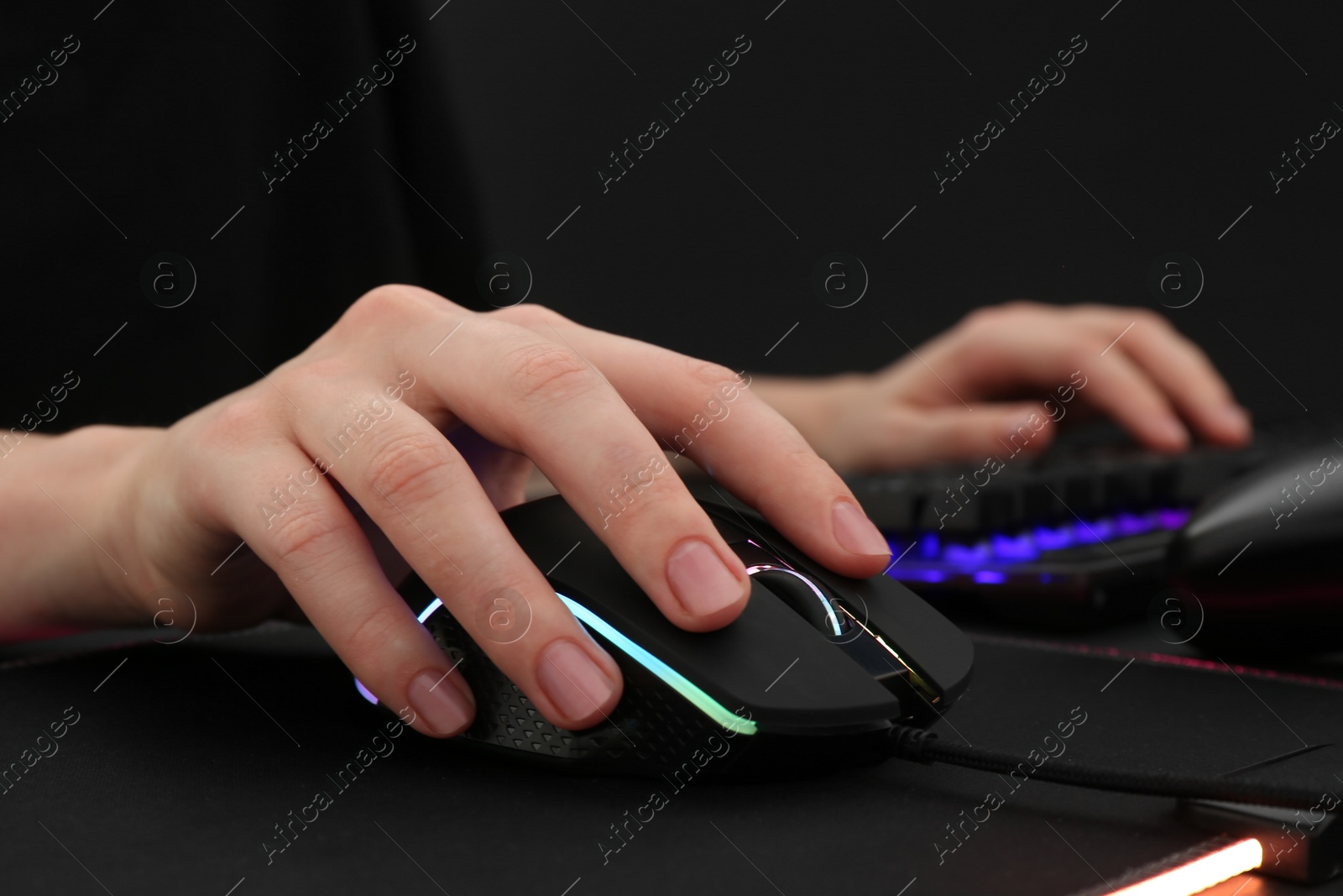 Photo of Gamer using modern wired computer mouse at dark table, closeup