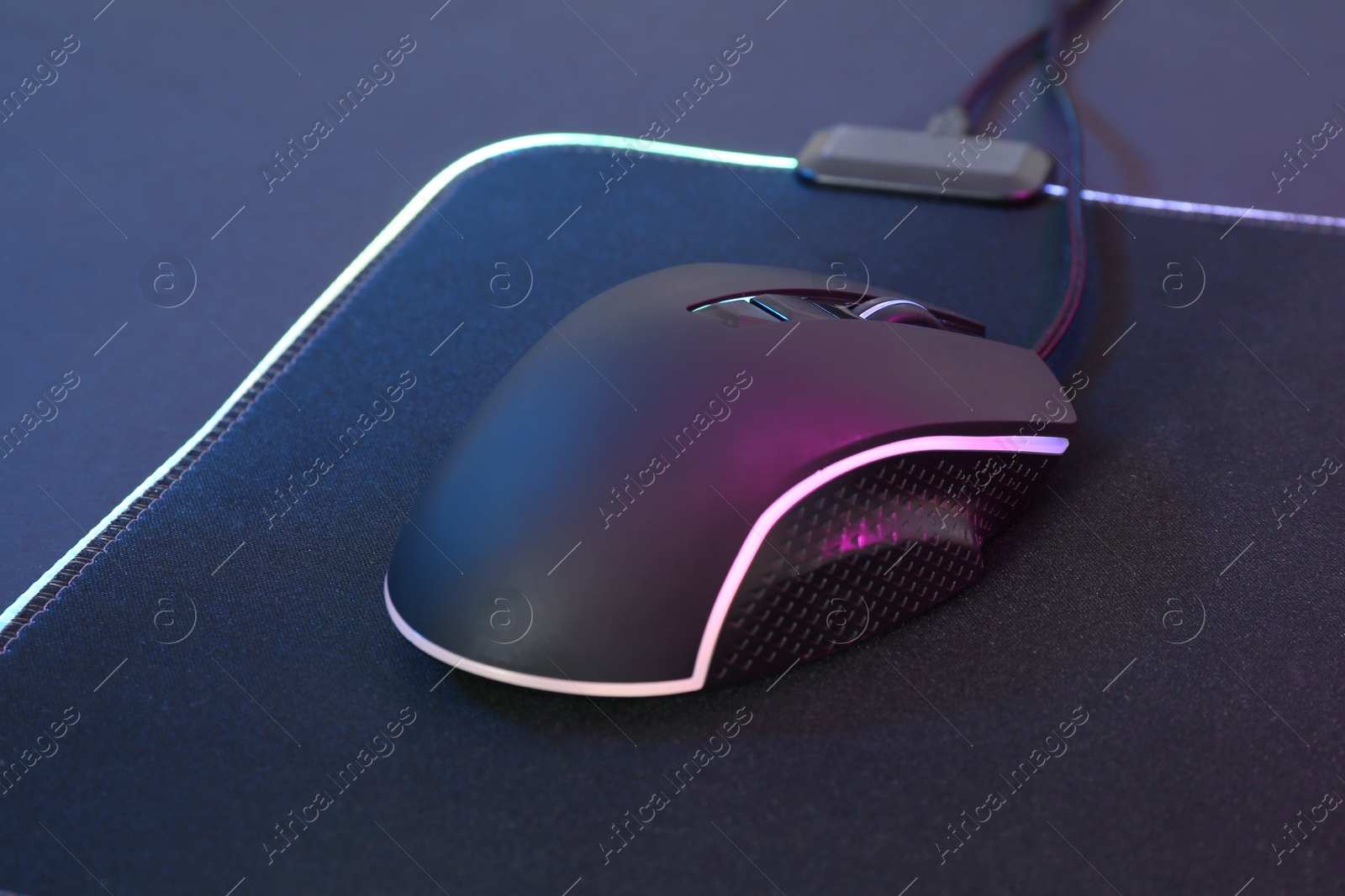 Photo of Computer mouse and mousepad on dark background, closeup