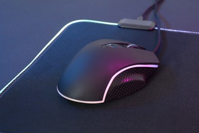 Photo of Computer mouse and mousepad on dark background, closeup