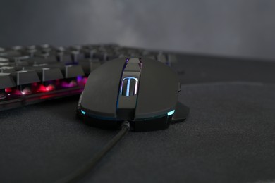 Photo of Computer mouse and RGB keyboard on dark background, closeup