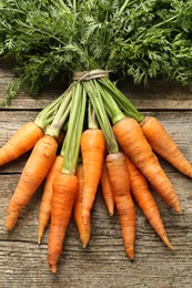 Bunch of tasty ripe juicy carrots on wooden table, top view