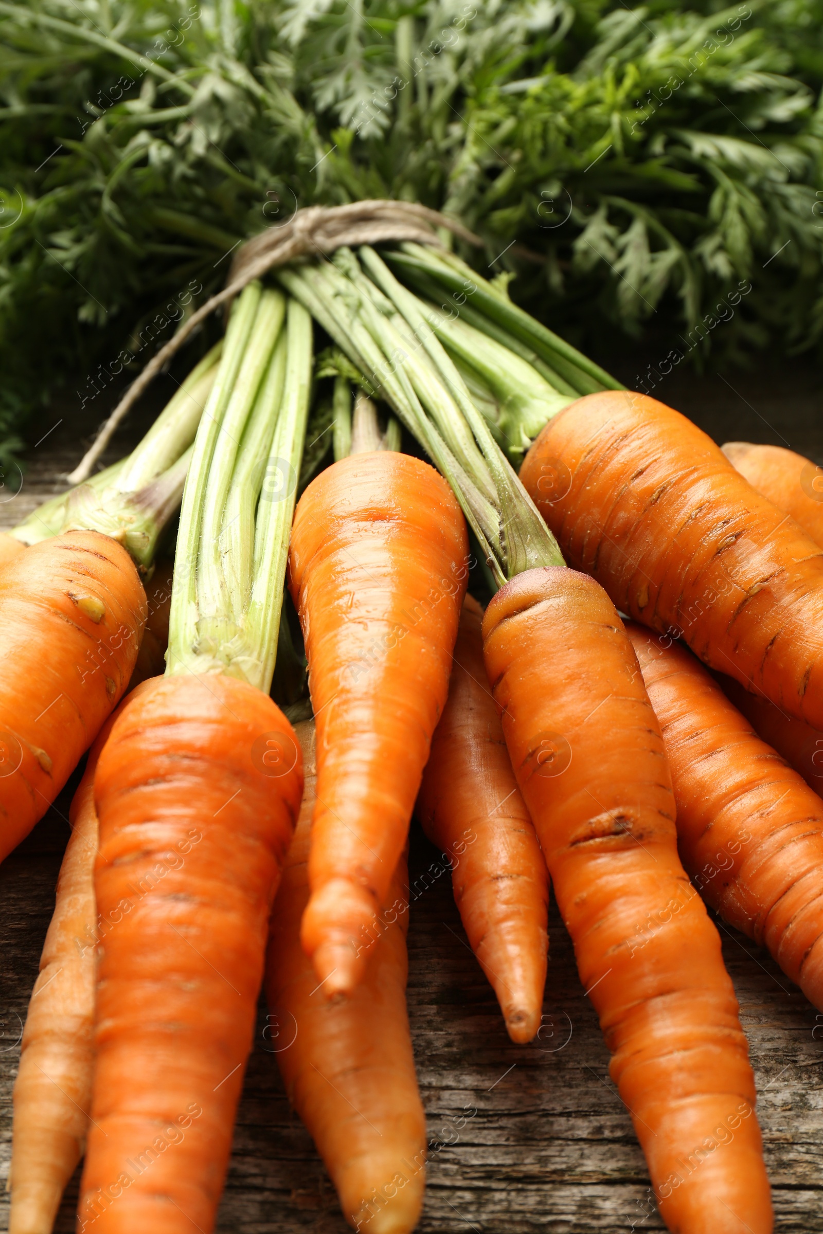 Photo of Bunch of tasty ripe juicy carrots on wooden table, closeup