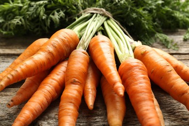 Bunch of tasty ripe juicy carrots on wooden table, closeup