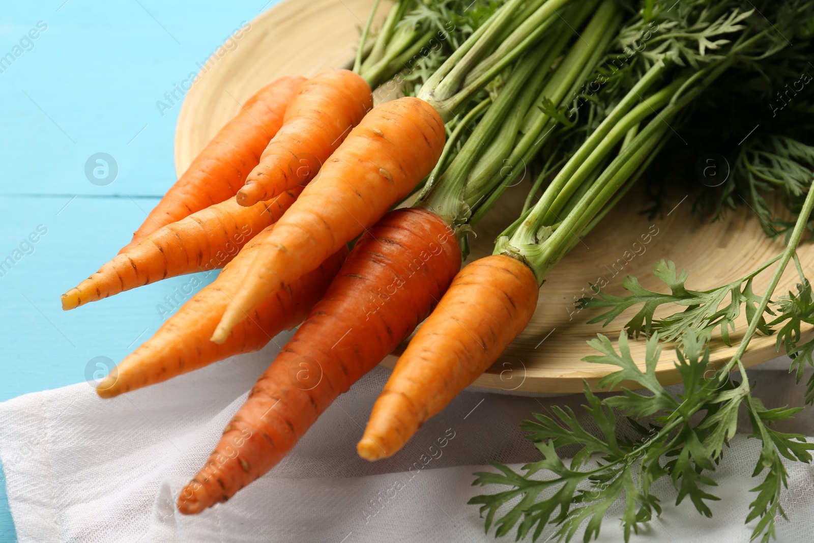 Photo of Tasty ripe juicy carrots on light blue wooden table