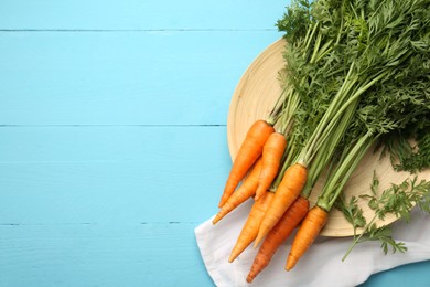 Photo of Tasty ripe juicy carrots on light blue wooden table, flat lay. Space for text