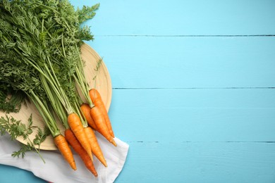 Photo of Tasty ripe juicy carrots on light blue wooden table, flat lay. Space for text