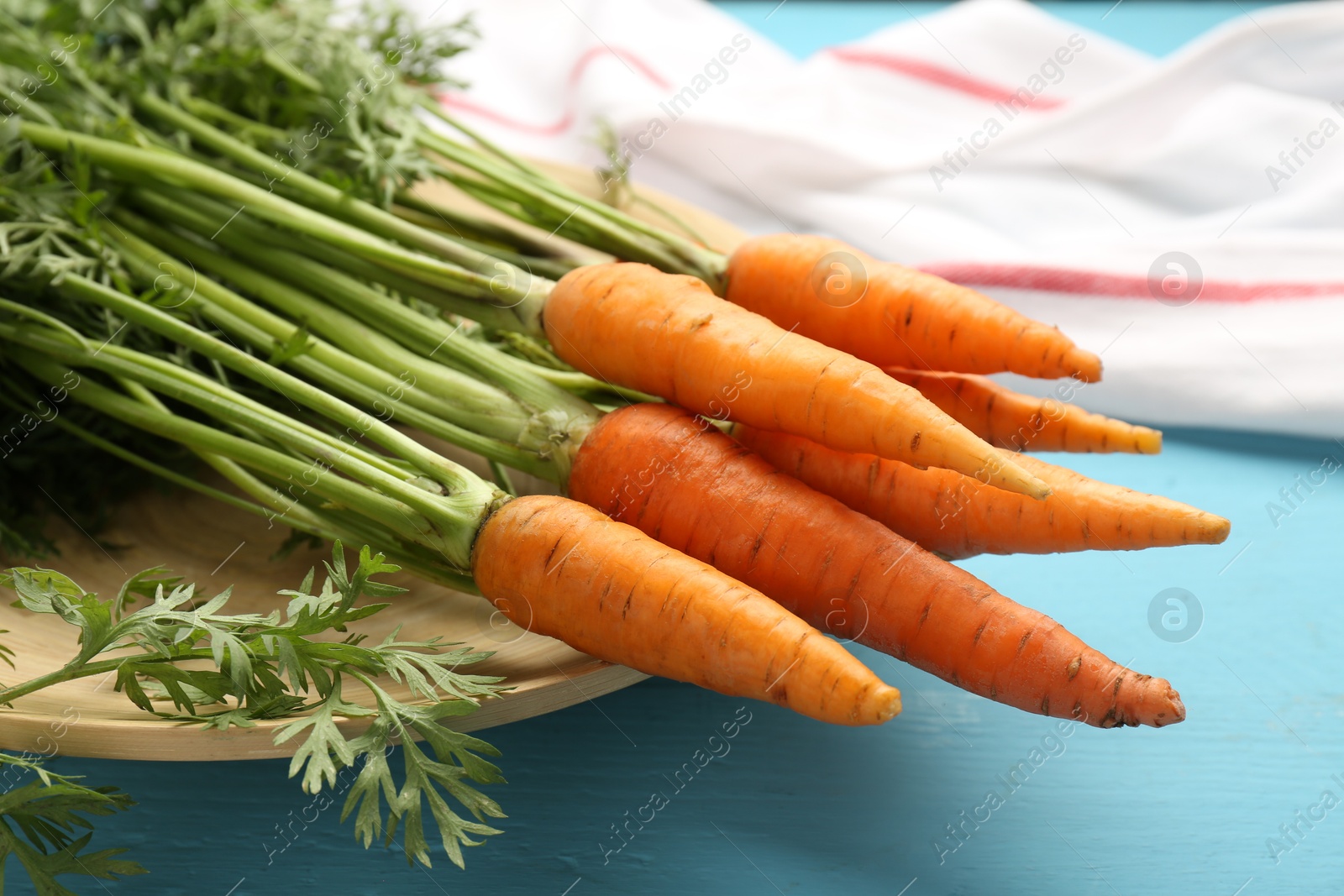 Photo of Tasty ripe juicy carrots on light blue wooden table, closeup