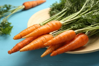 Photo of Tasty ripe juicy carrots on light blue wooden table, closeup