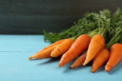 Photo of Tasty ripe juicy carrots on light blue wooden table, closeup