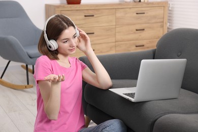 Teenager in headphones having video chat via laptop at home. Remote work