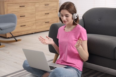 Teenager in headphones having video chat via laptop at home. Remote work