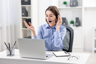 Teenager in headset having video chat via laptop at home. Remote work