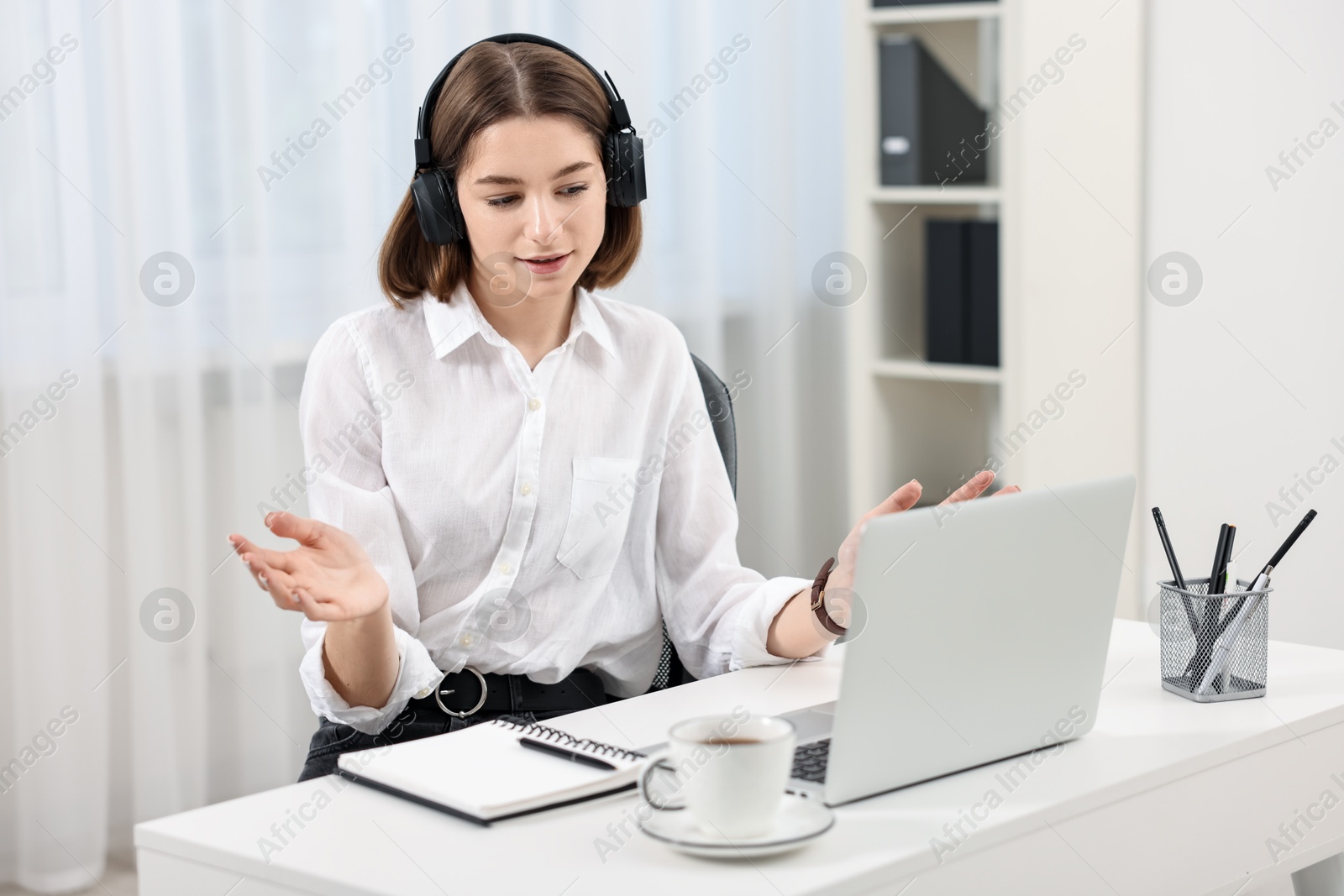 Photo of Teenager in headset having video chat via laptop at home. Remote work