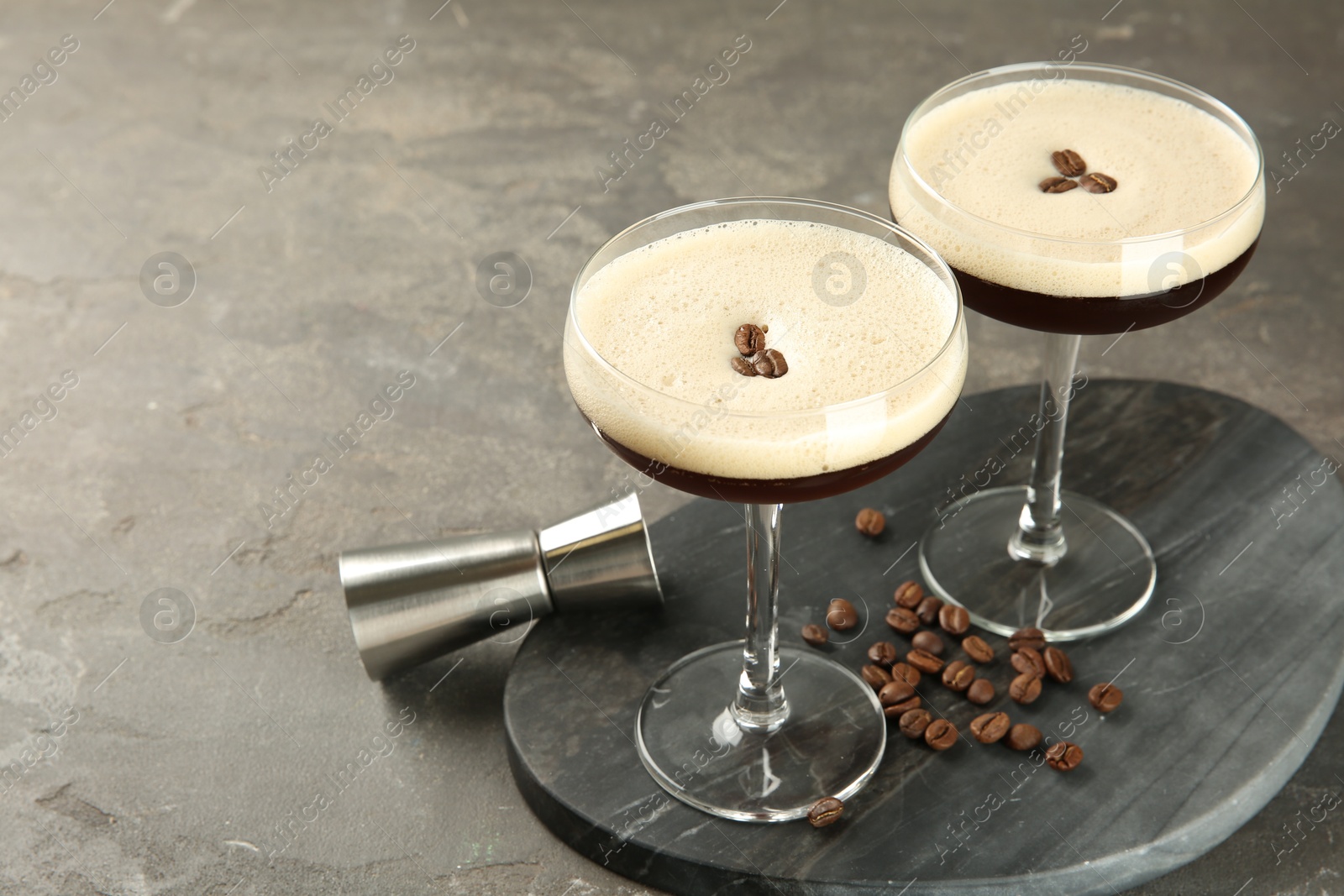 Photo of Espresso Martini cocktail in glasses and beans on grey textured table