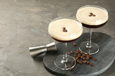 Photo of Espresso Martini cocktail in glasses and beans on grey textured table