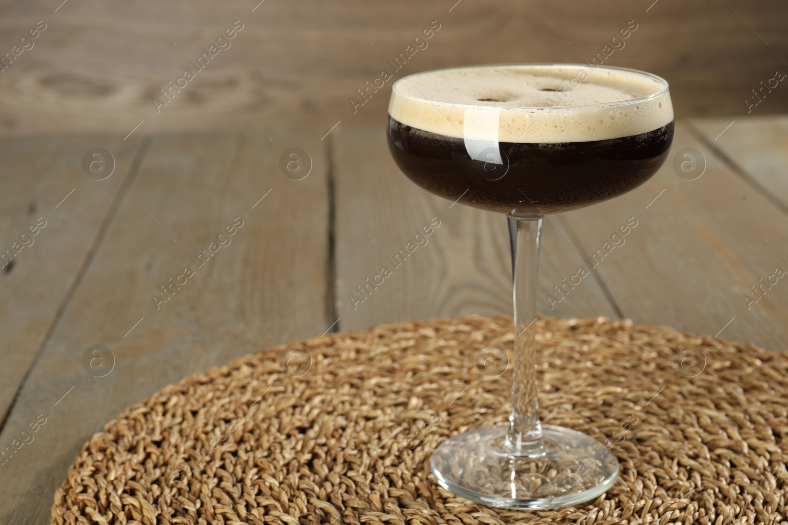 Photo of Glass of fresh coffee cocktail on wooden table, space for text