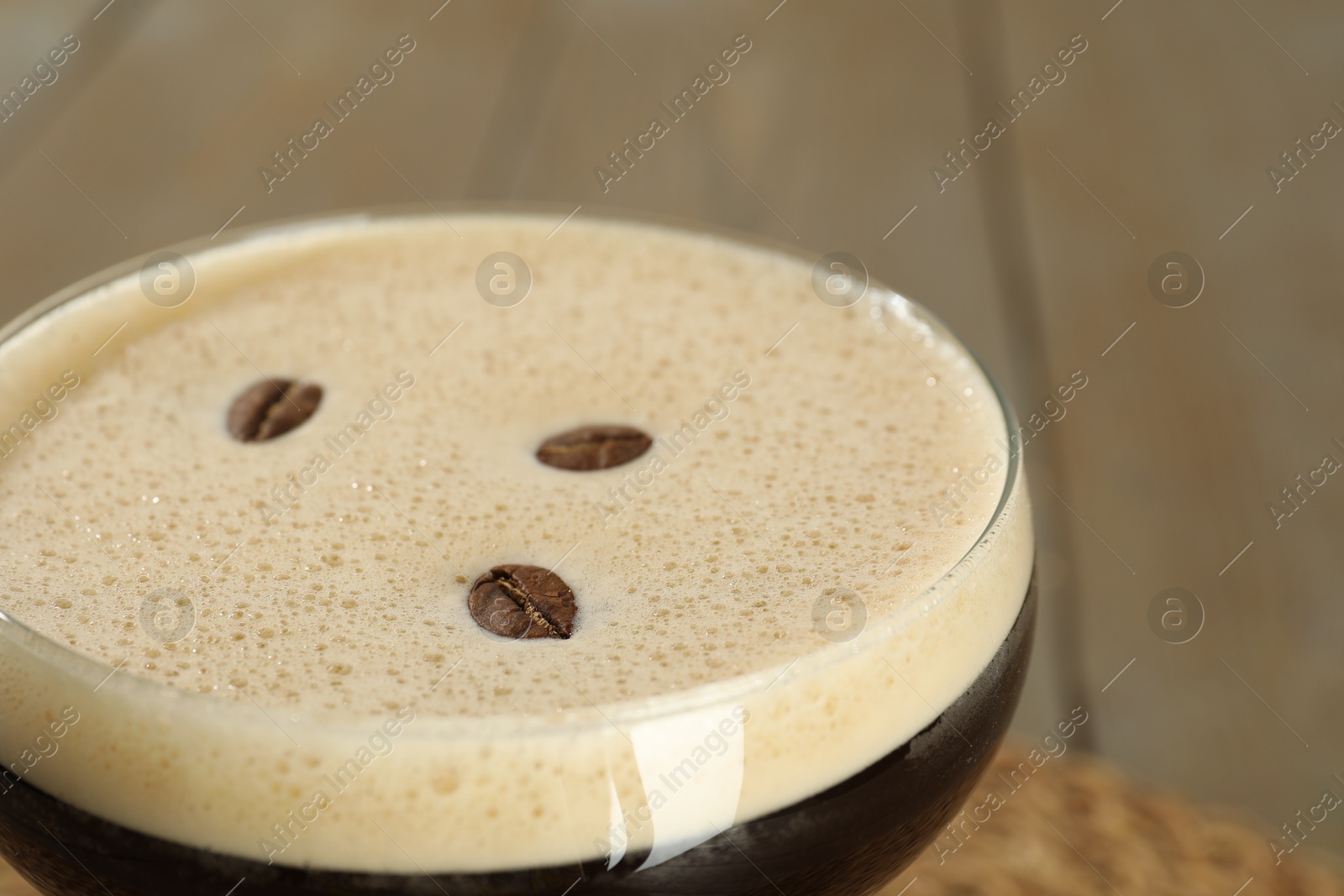 Photo of Glass of fresh coffee cocktail on light table, closeup