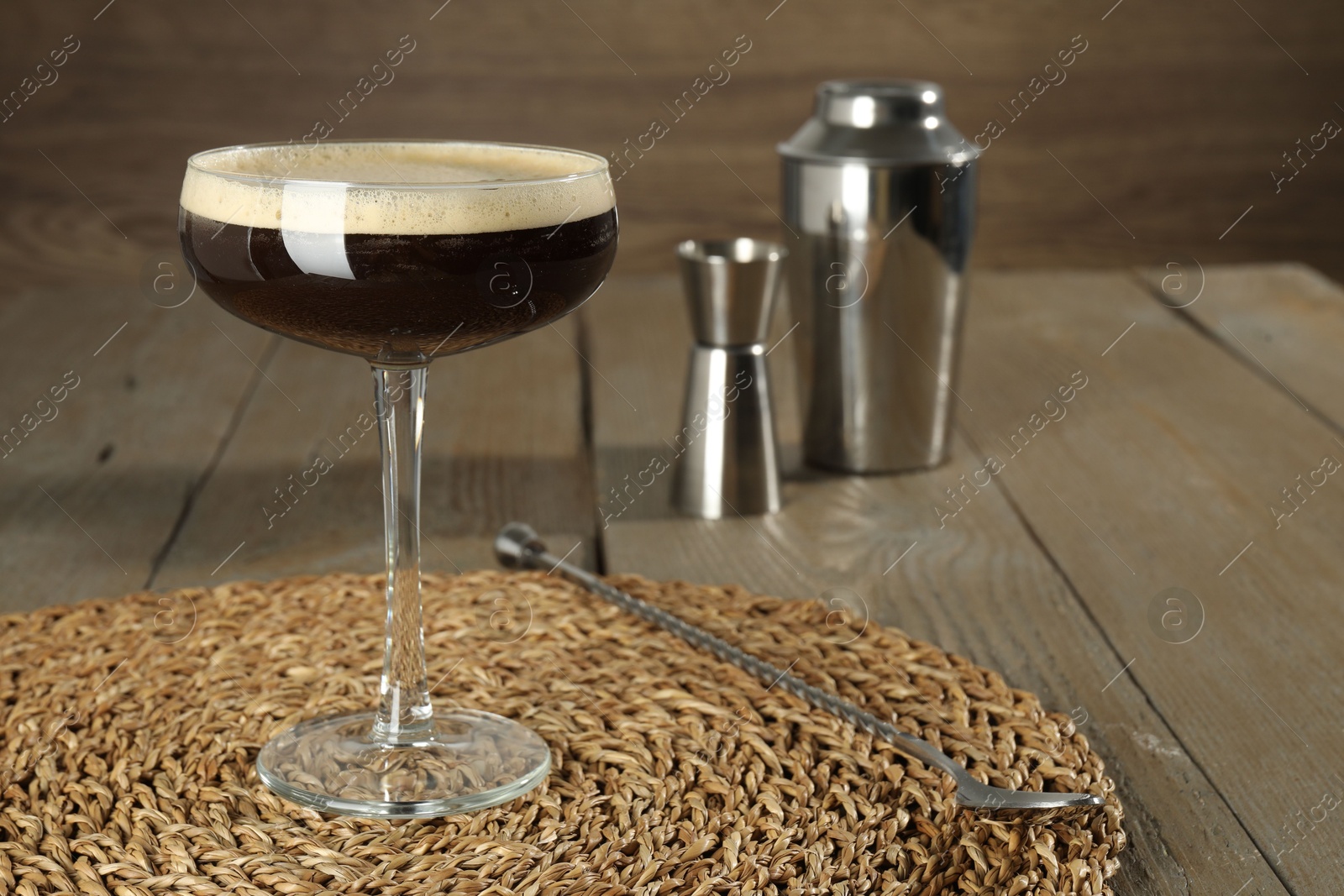 Photo of Glass of fresh coffee cocktail and bartender equipment on wooden table