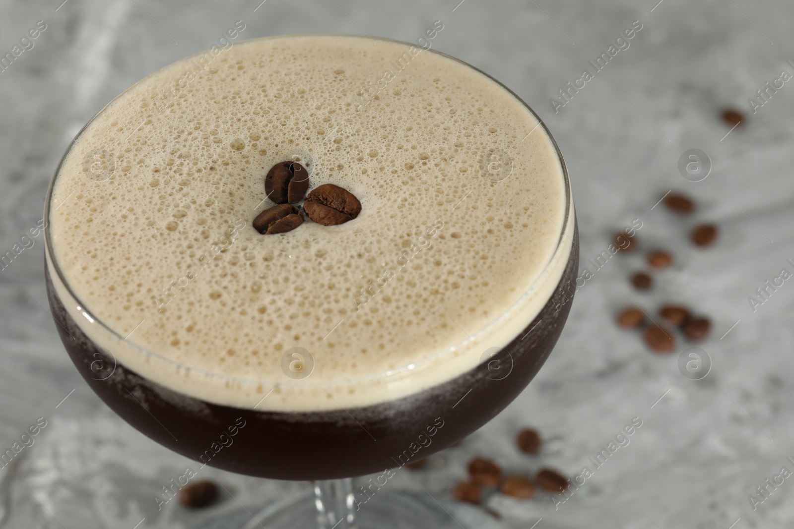 Photo of Glass of fresh coffee cocktail on gray table, closeup