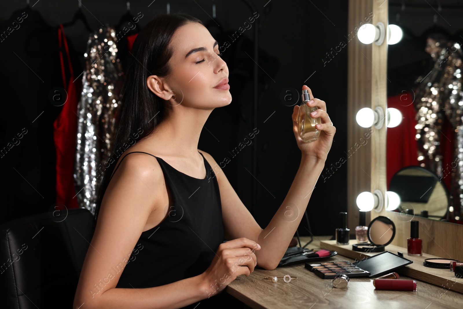 Photo of Beautiful woman spraying perfume in makeup room