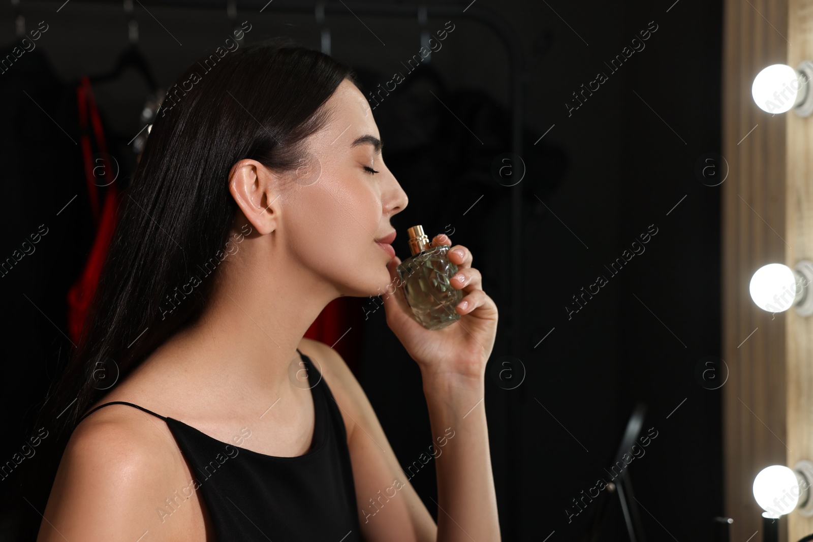 Photo of Beautiful woman with bottle of perfume in makeup room