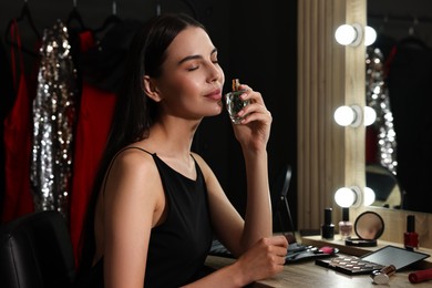 Photo of Beautiful woman with bottle of perfume in makeup room