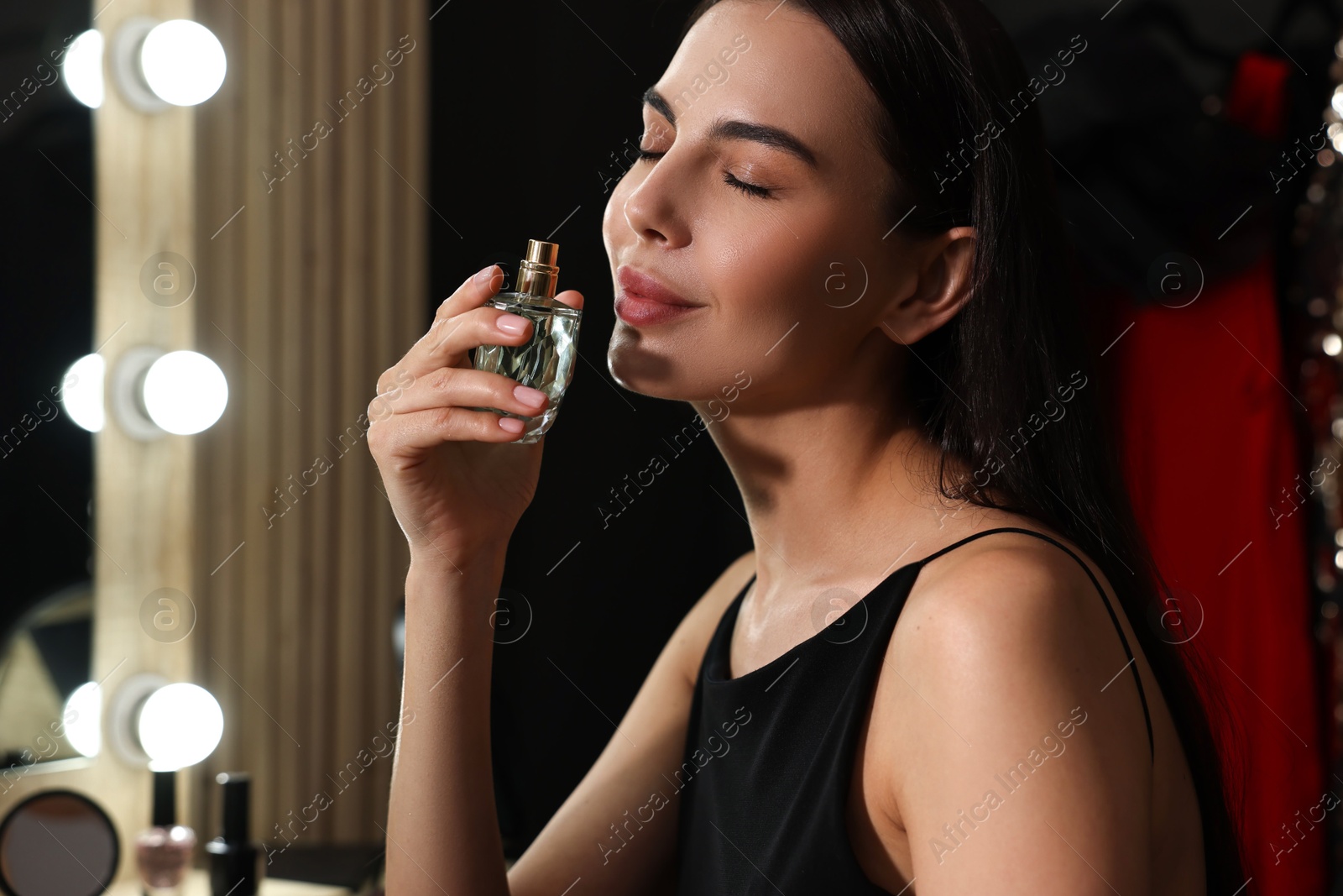 Photo of Beautiful woman with bottle of perfume in makeup room