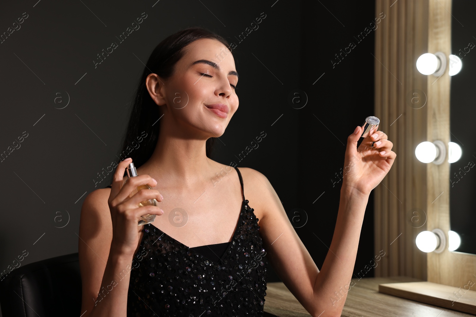 Photo of Beautiful woman spraying perfume in makeup room