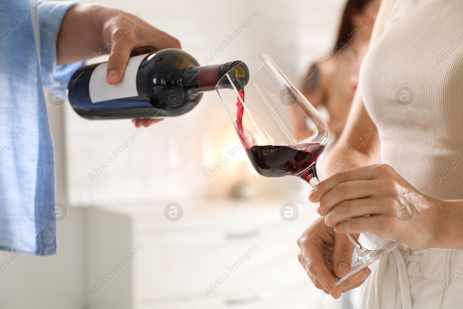 Photo of Man pouring red wine into woman`s glass indoors, selective focus