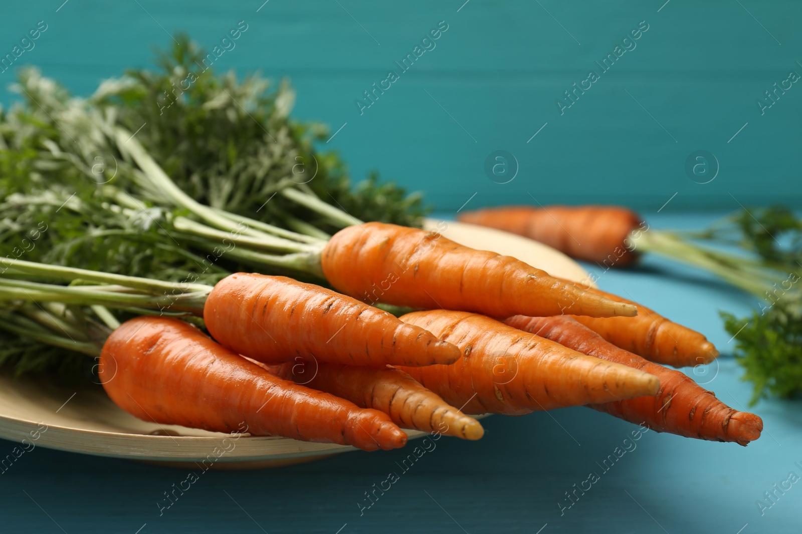 Photo of Tasty ripe juicy carrots on light blue wooden table, closeup